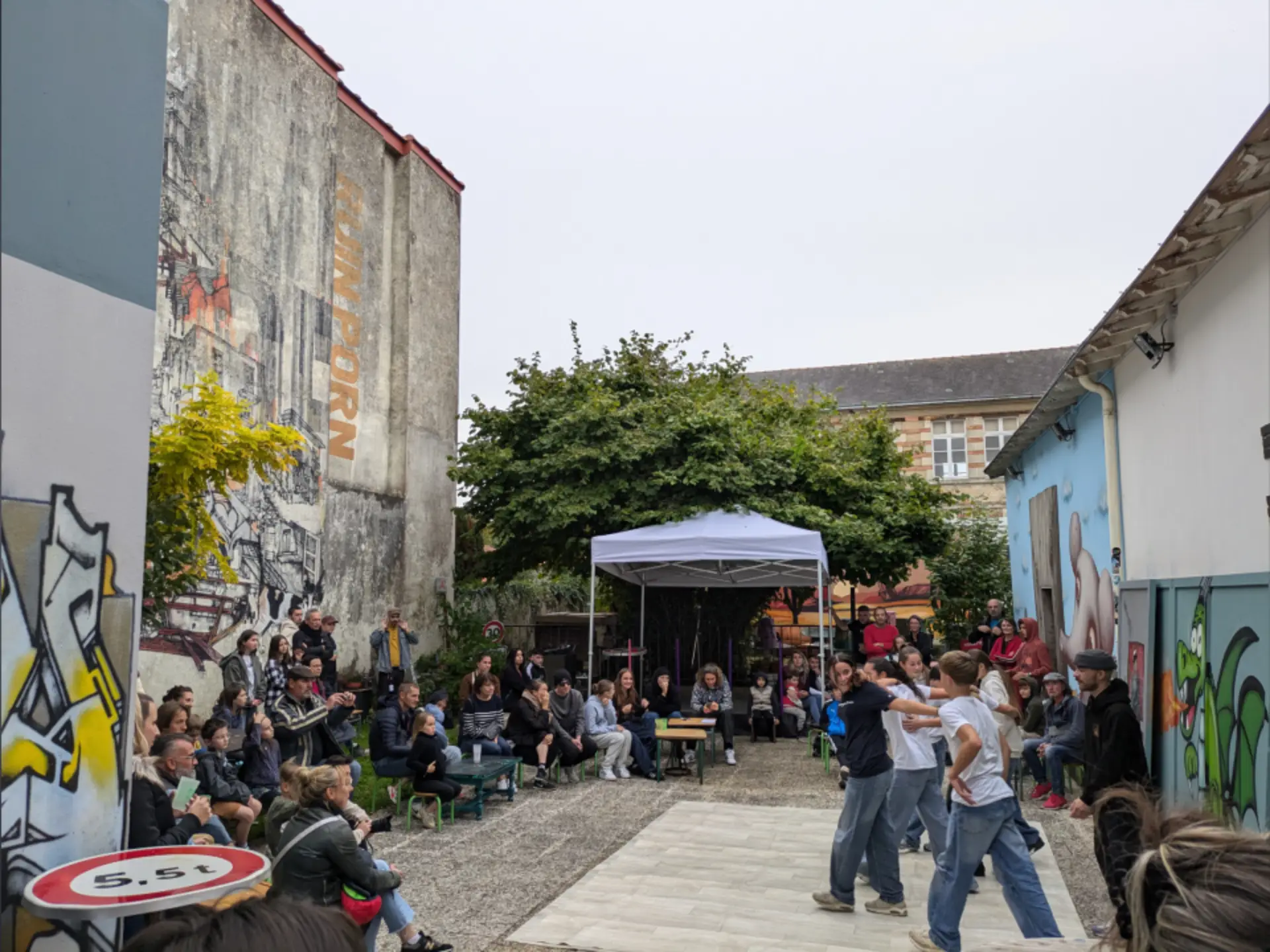 rassemblement de personnes dans la cours de l'association, des jeunes font du hiphop au milieu