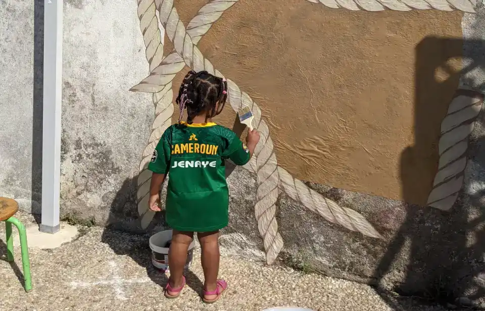 une petite fille en train de peindre des cordes de beateau