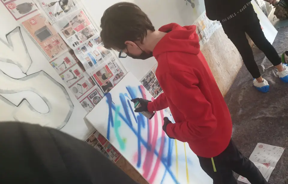 un ado en train d'apprendre a utiliser une bombe aérosol