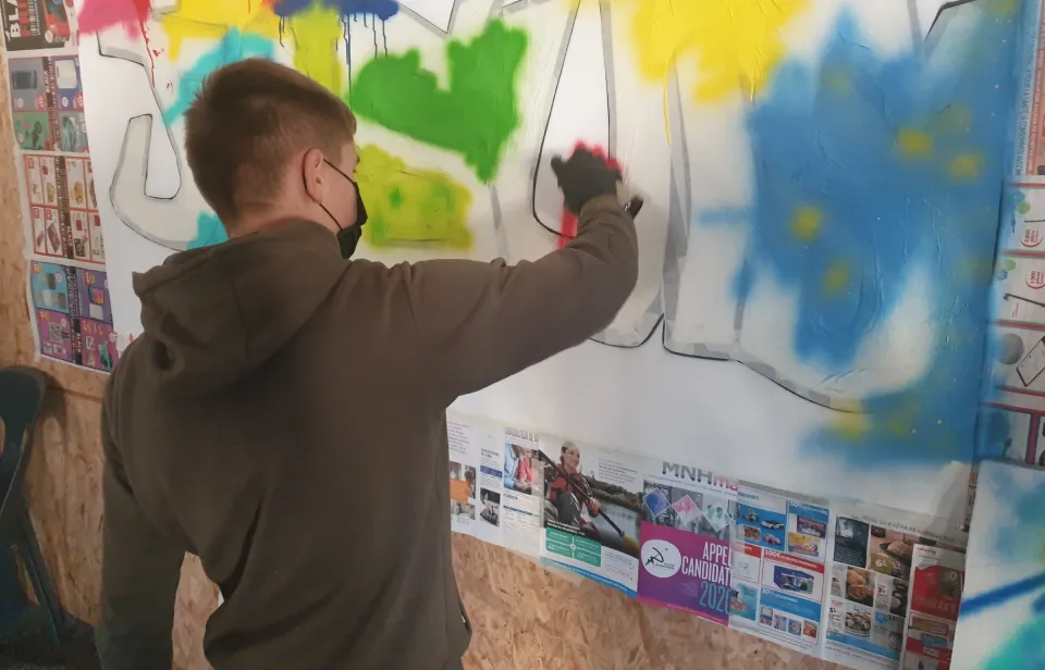 un ado en train d'apprendre a utiliser une bombe aérosol