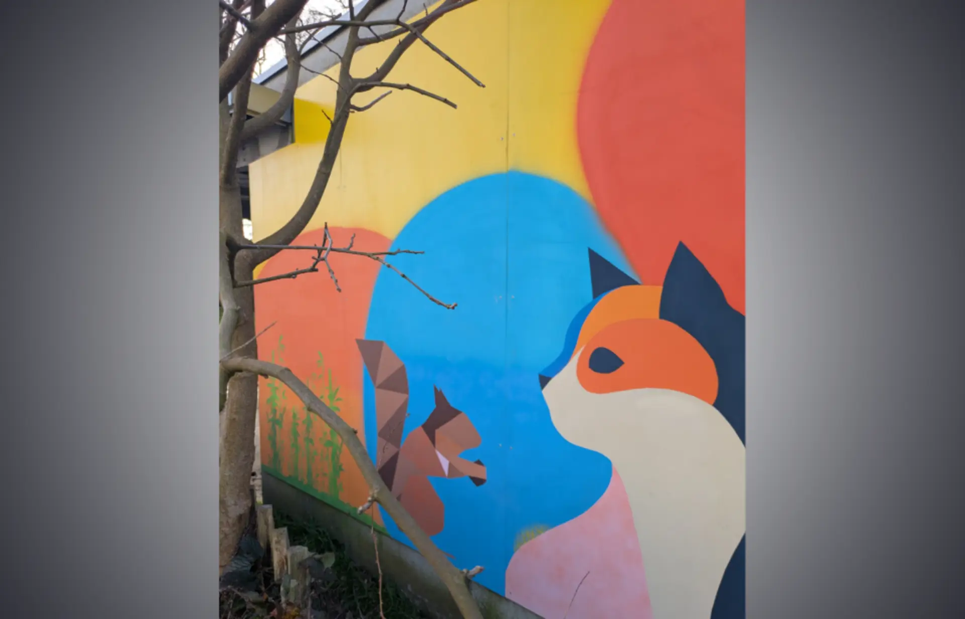 Peinture murale extérieure avec un chat stylisé aux couleurs vives et un écureuil brun sur fond de cercles colorés.