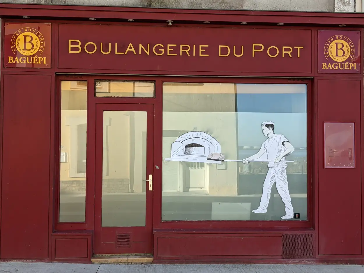 collage d'un boulange mettant du pain au four sur la devanture d'une boulangerie